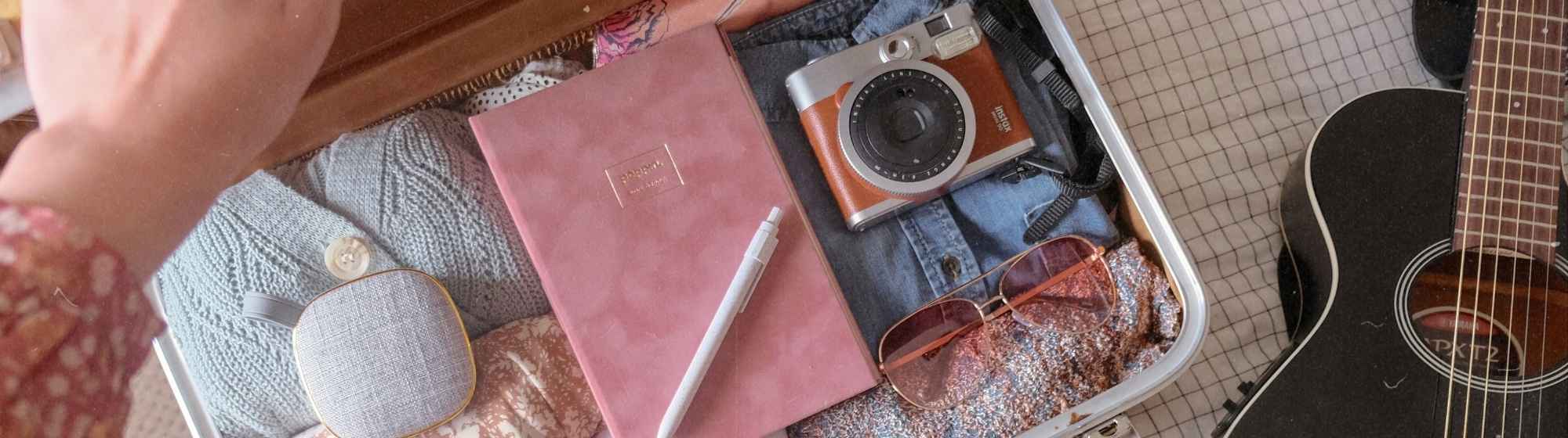 Valise ouverte avec accessoires de voyage et appareil photo