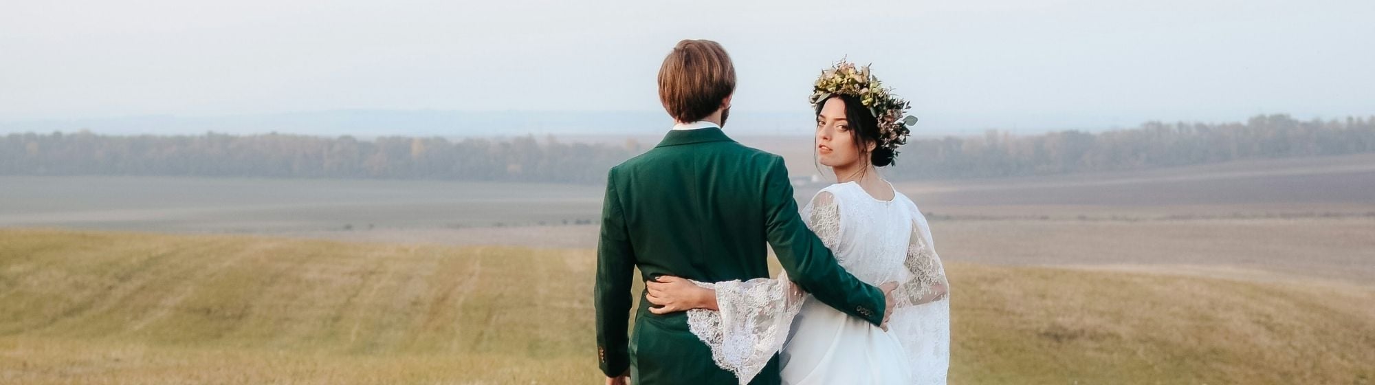 couple maries marchant dans champ mariage champetre robe blanche couronne de fleurs paysage nature